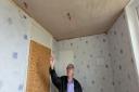Cllr Christ Loftus inspects bathroom damage in one of the homes