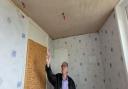 Cllr Christ Loftus inspects bathroom damage in one of the homes