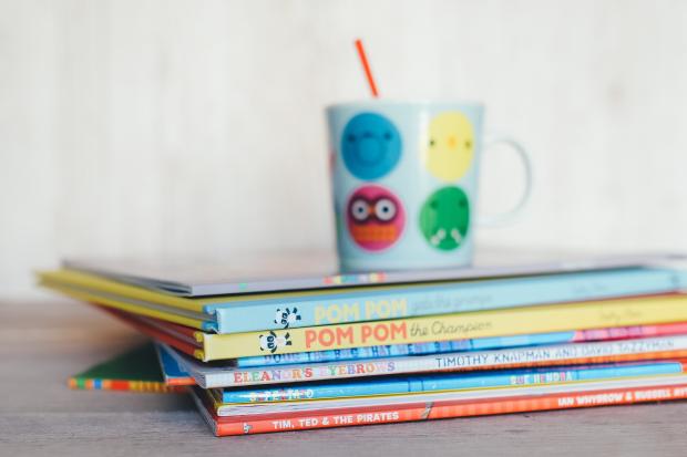 Runcorn and Widnes World: Children's books in a pile with a colourful mug on top. Credit: Canva